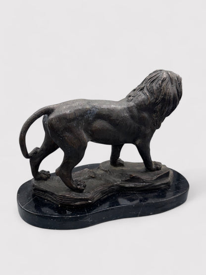 Seitliche Ansicht. Bronzeskulptur eines stehenden Löwen in Dunkelbraun und Schwarz, 24 cm hoch und 30 cm lang; aus massiver Bronze gefertigt, geeignet für Innen- und Außenbereiche. Detaillierte Verarbeitung mit natürlicher Patina, die dem Löwen einen antiken Charakter verleiht. Artikelnummer 0044.