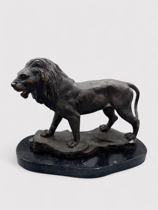 Seitliche Ansicht. Bronzeskulptur eines Löwen in Dunkelbraun und Schwarz, 24 cm hoch und 30 cm lang; aus massiver Bronze gefertigt, geeignet für Innen- und Außenbereiche. Detaillierte Verarbeitung mit natürlicher Patina, die dem Löwen einen antiken Charakter verleiht. Artikelnummer 0044.